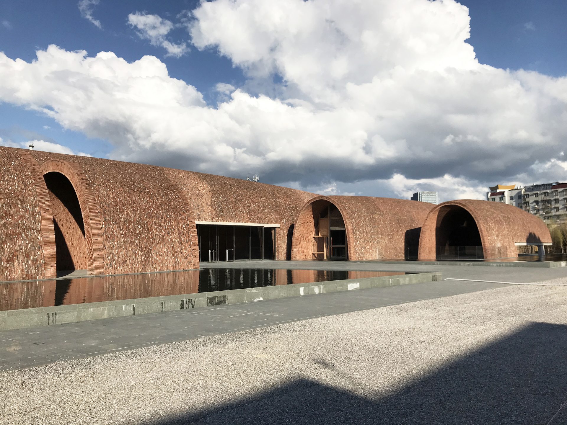 Red-brick arched kiln-inspired buildings of Jingdezhen Imperial Kiln Museum reflected in a pool — Photo: Zhu Pei / CC BY-SA 4.0 via Wikimedia Commons