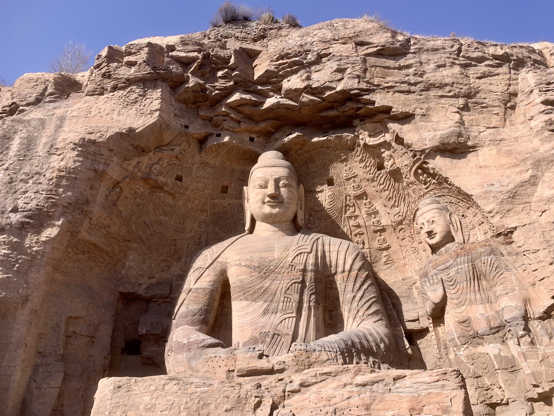The seated open-air Buddha of Cave 20 carved into the sandstone cliff at Yungang Grottoes, Datong