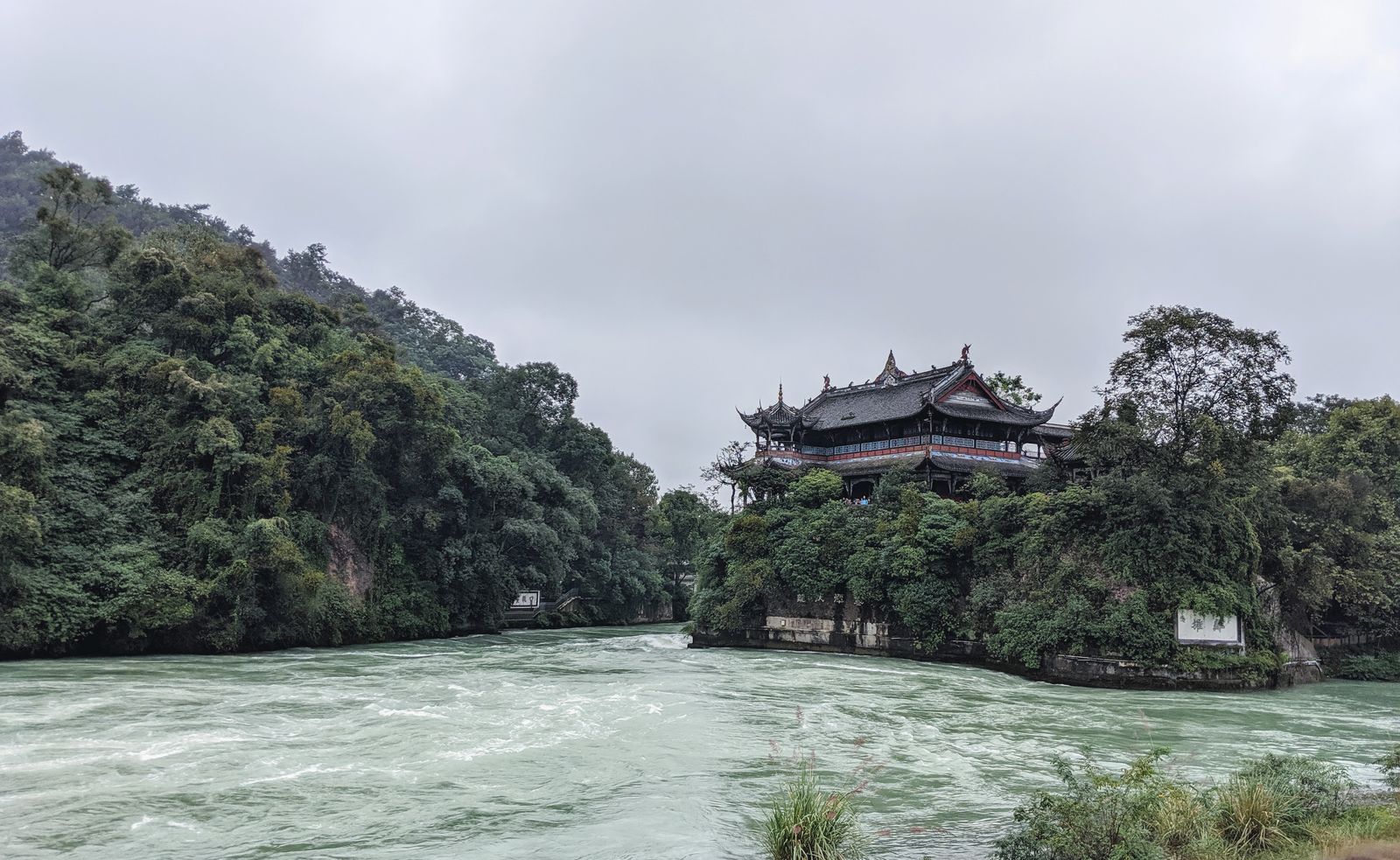 Die Flaschenhals-Lücke in Dujiangyan, wo der Min-Fluss zwischen Felswänden zusammengedrückt wird, um Wasser auf die Chengdu-Ebene zu dosieren, mit den Tempelhallen von Lidui darüber