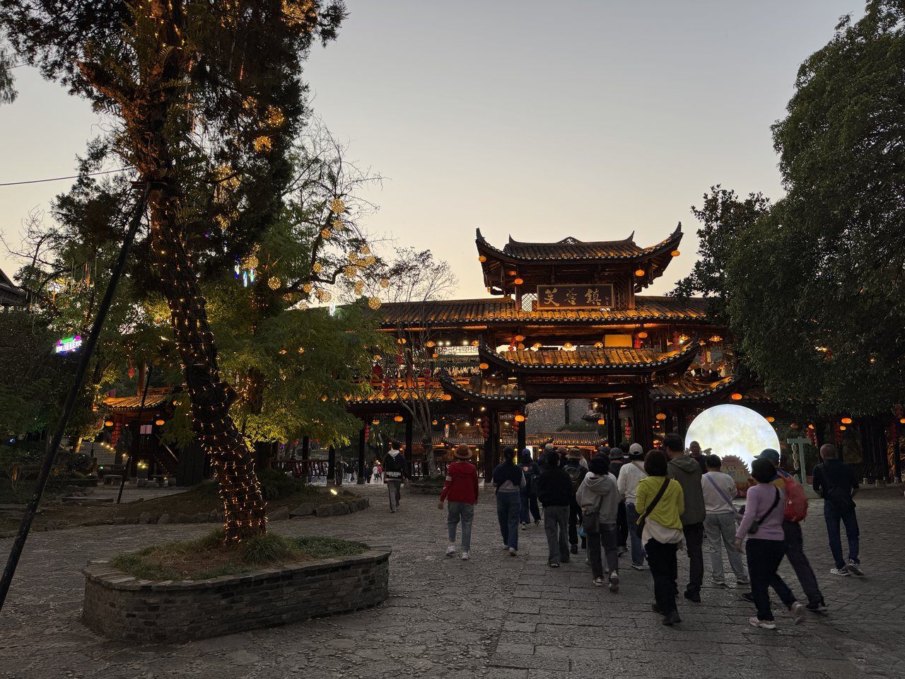 The entrance gate of Furong Town at dusk — the ticket checkpoint sits here, and the waterfall is on the other side of it