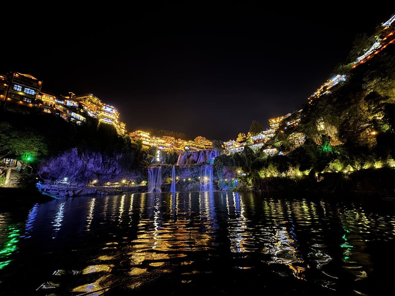 Furong Town lit after dark, the waterfall running down through the middle of the town into the Youshui river