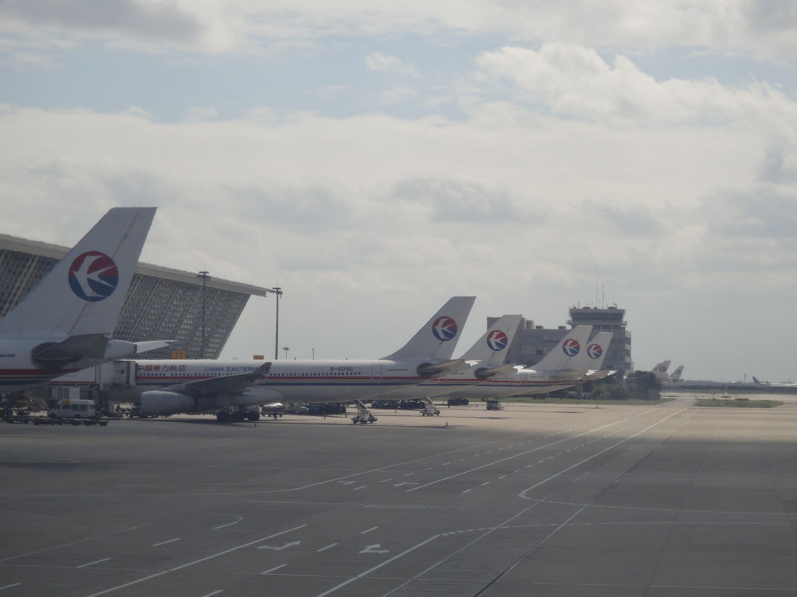A line of China Eastern aircraft on the apron at Pudong, with the Terminal 1 building and control tower behind them