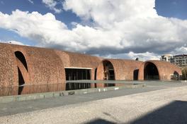 Red-brick arched kiln-inspired buildings of Jingdezhen Imperial Kiln Museum reflected in a pool — Photo: Zhu Pei / CC BY-SA 4.0 via Wikimedia Commons