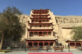 The nine-storey red timber facade of Cave 96 at Mogao Caves built into the desert cliff, Dunhuang — Photo: 慕尼黑啤酒 / CC BY-SA 3.0 via Wikimedia Commons