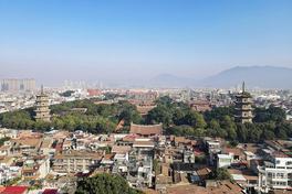 Aerial view over Quanzhou's old city: the twin stone pagodas of Kaiyuan Temple rising either side of the temple complex, with red-tiled roofs of Licheng district in the foreground — Photo: Windmemories / CC BY-SA 4.0 via Wikimedia Commons